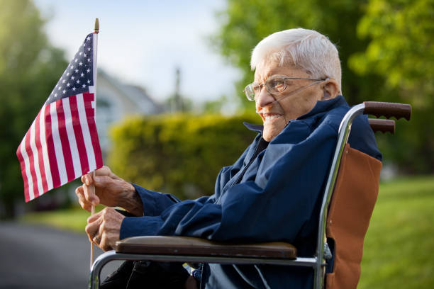 elderly American veteran holding a U.S. flag while sitting in a wheelchair